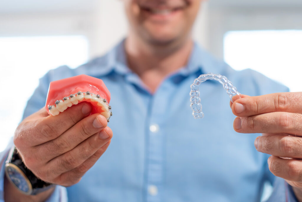 A doctor showing traditional braces and clear aligners