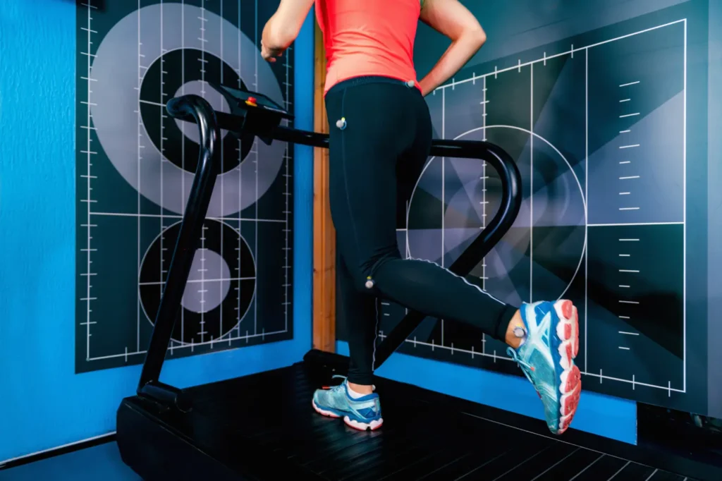A woman in a bright red shirt and leggings jogging on a treadmill