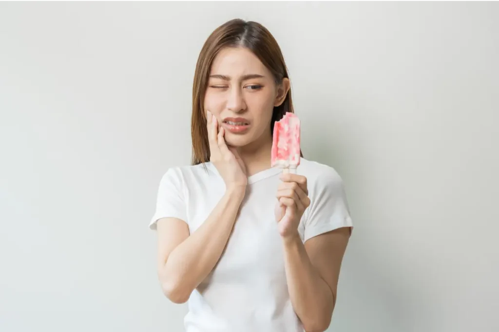 A lady experiencing sensitivity from a popsicle ice cream, requiring a dentist for toothache