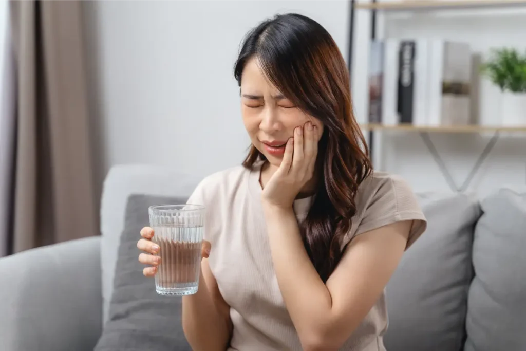 A lady experiencing tooth sensitivity from cold water, requiring a dentist for toothache
