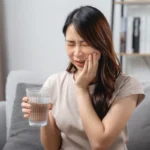 A lady experiencing tooth sensitivity from cold water, requiring a dentist for toothache