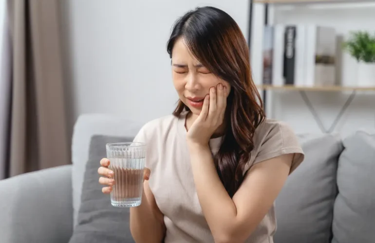 A lady experiencing tooth sensitivity from cold water, requiring a dentist for toothache