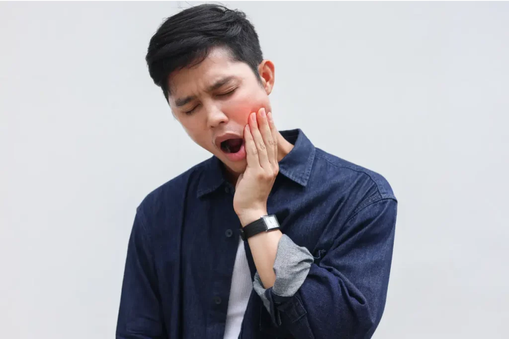 A man experiencing TMJ pain when he opens his mouth, requiring a dentist for toothache