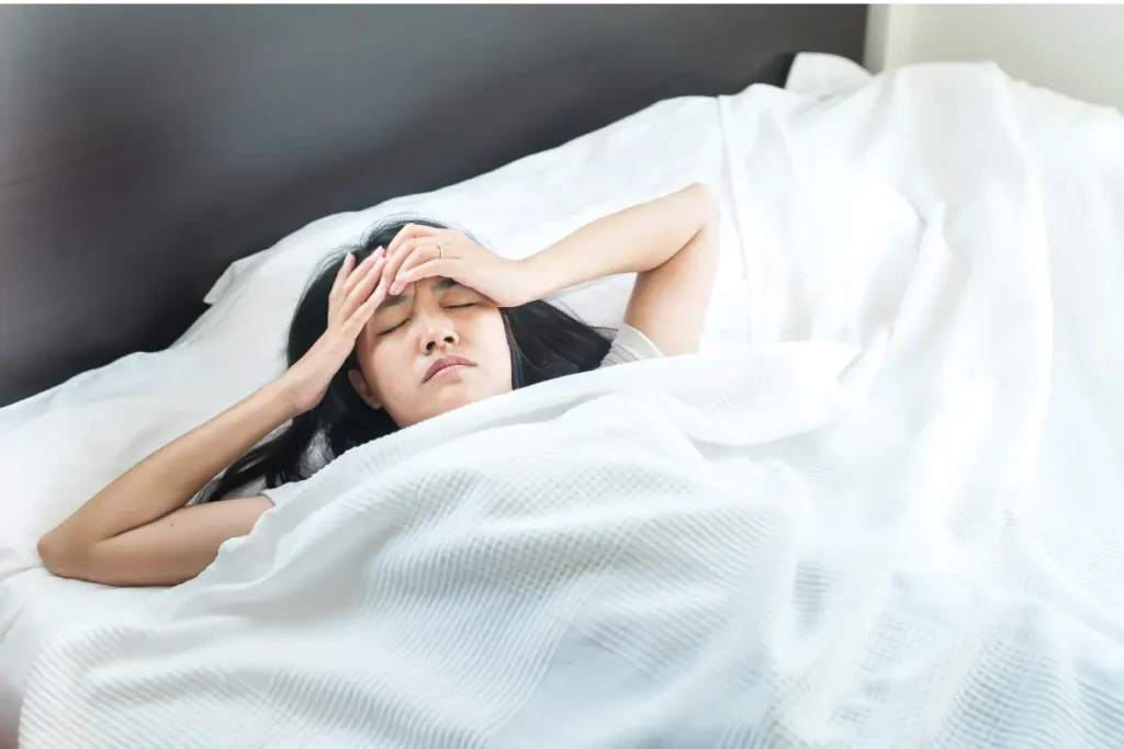 A woman experiencing temple pain as she wakes up, requiring a dentist for toothache