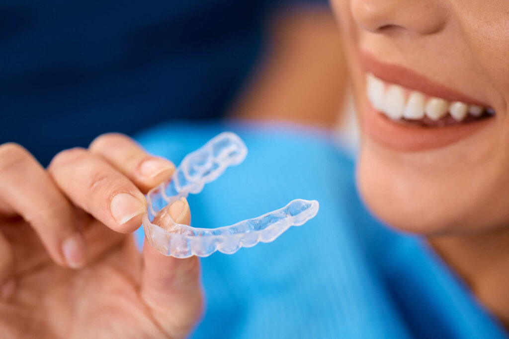 a woman holding her clear aligner instead of having a dental extraction in Singapore