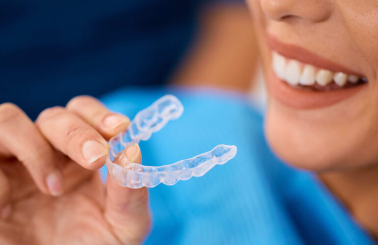 a woman holding her clear aligner instead of having a dental extraction in Singapore